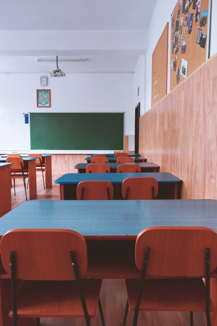 services-02 A tranquil empty classroom with wooden furniture and a green chalkboard, perfect for educational themes.